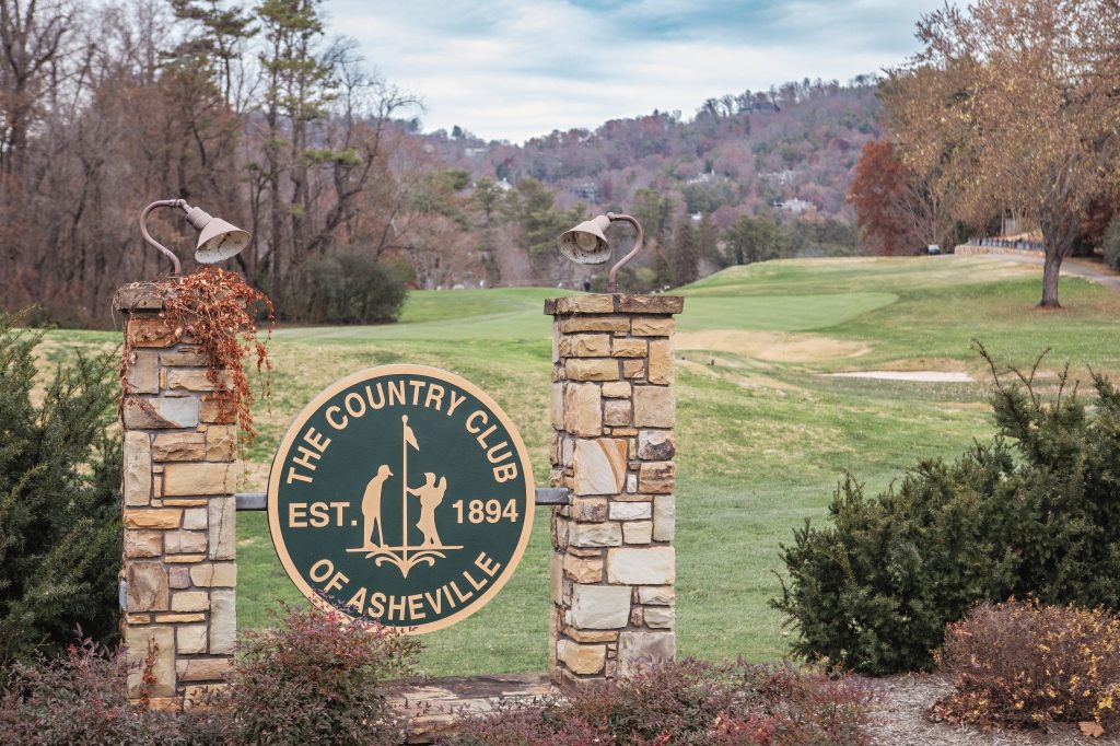 The Country Club of Asheville entrance sign, established 1894, with the course and North Asheville hills beyond