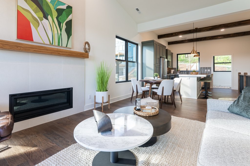 Great room with linear fireplace, beam ceiling, and natural light